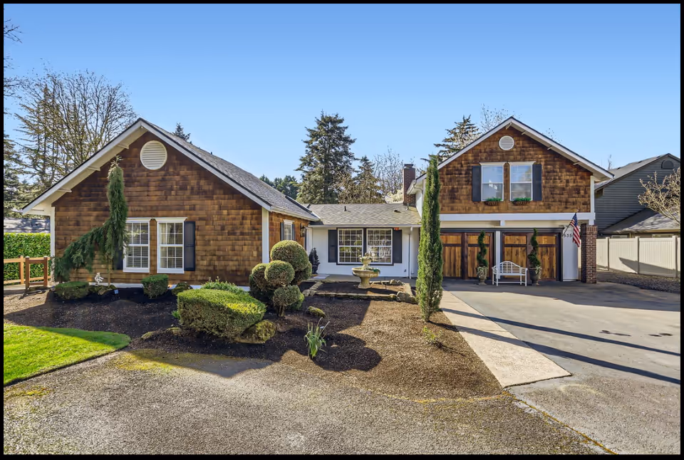 Two connected cottage-style buildings with a landscaped front yard and driveway.