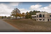 Exterior view of Elderwood at North Creek with building, lawn, trees, and parking area