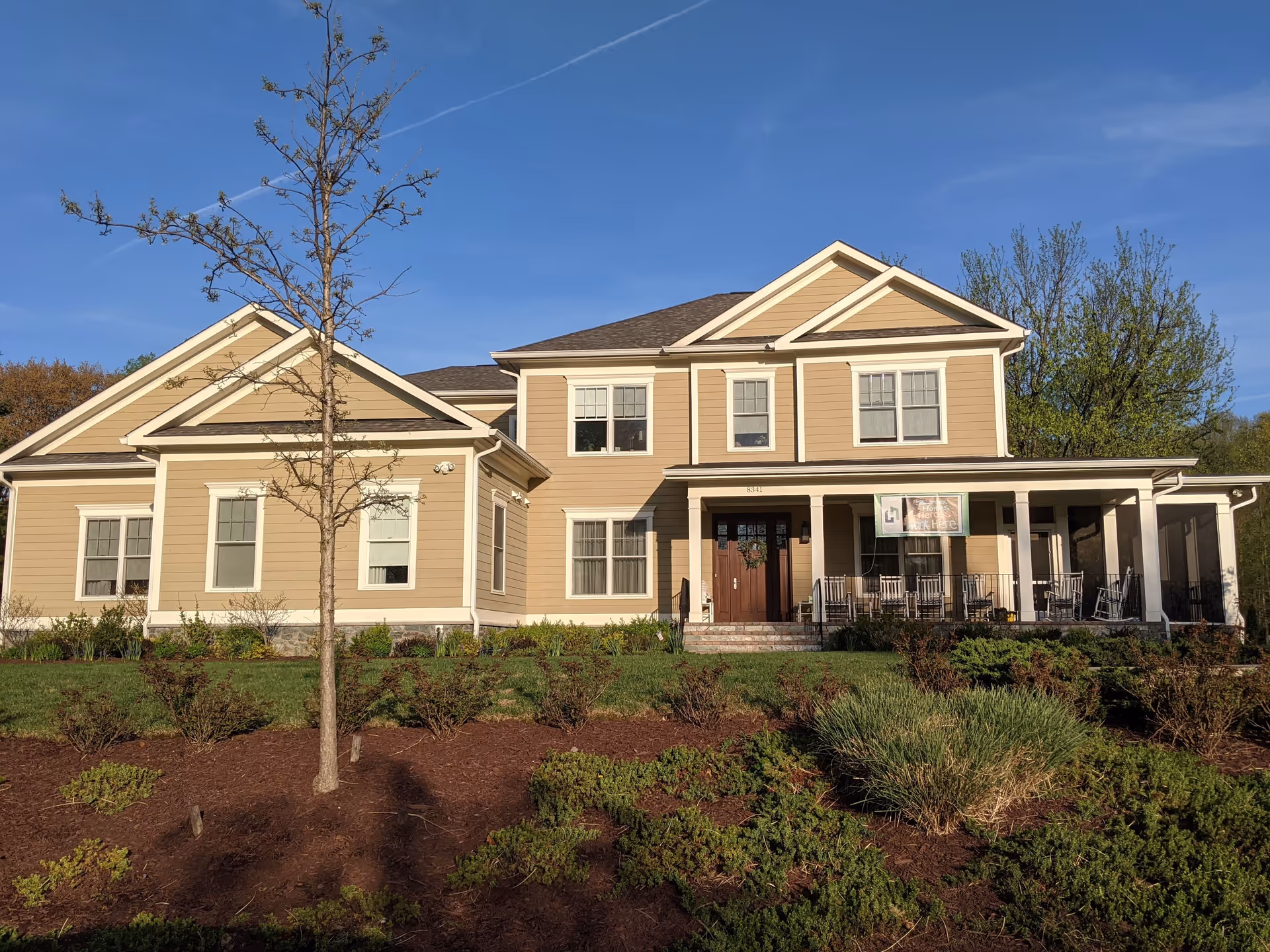 Beige two-story senior living building features a welcoming front porch and landscaped grounds.