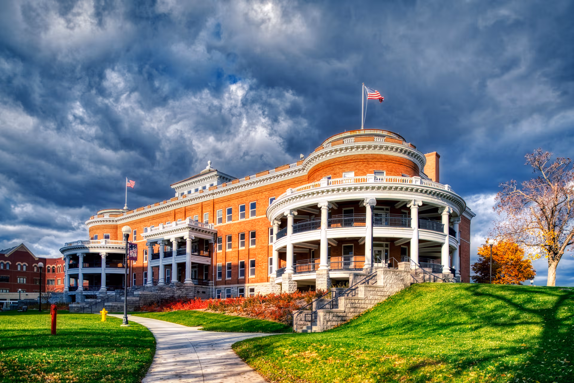 Red brick veterans home with curved white porches, steps, and a green lawn.
