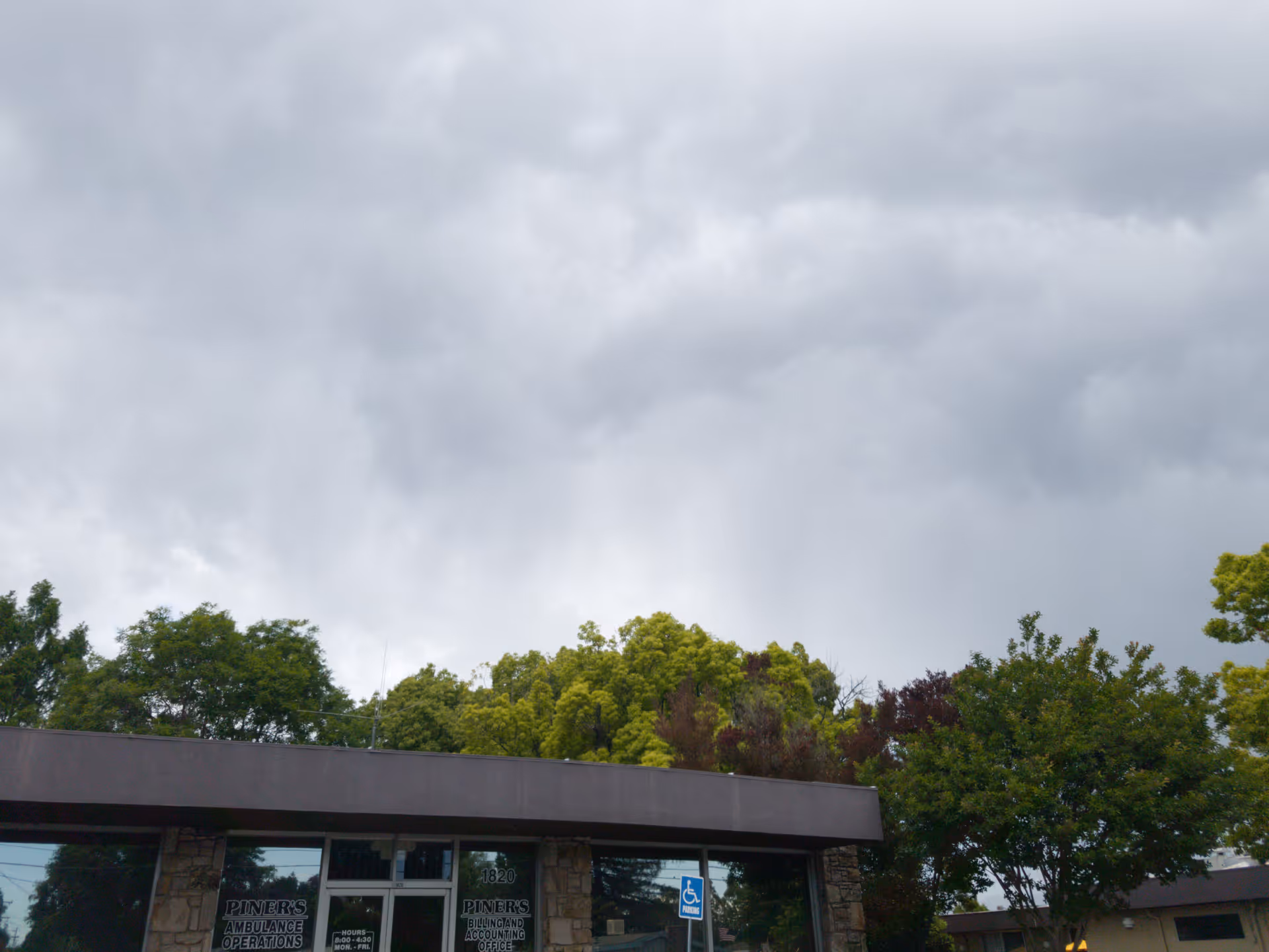 Exterior view of Piners Guest Home entrance with trees and cloudy sky.