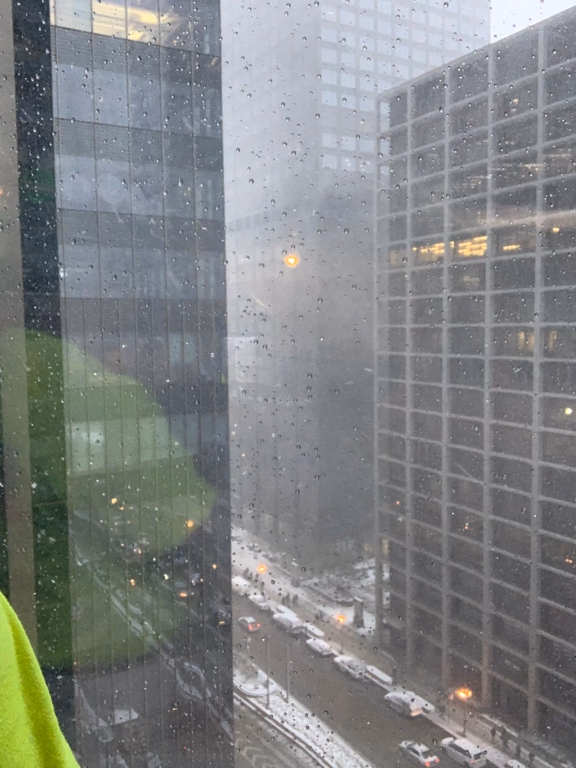 Rainy cityscape visible through a glass window with raindrops.