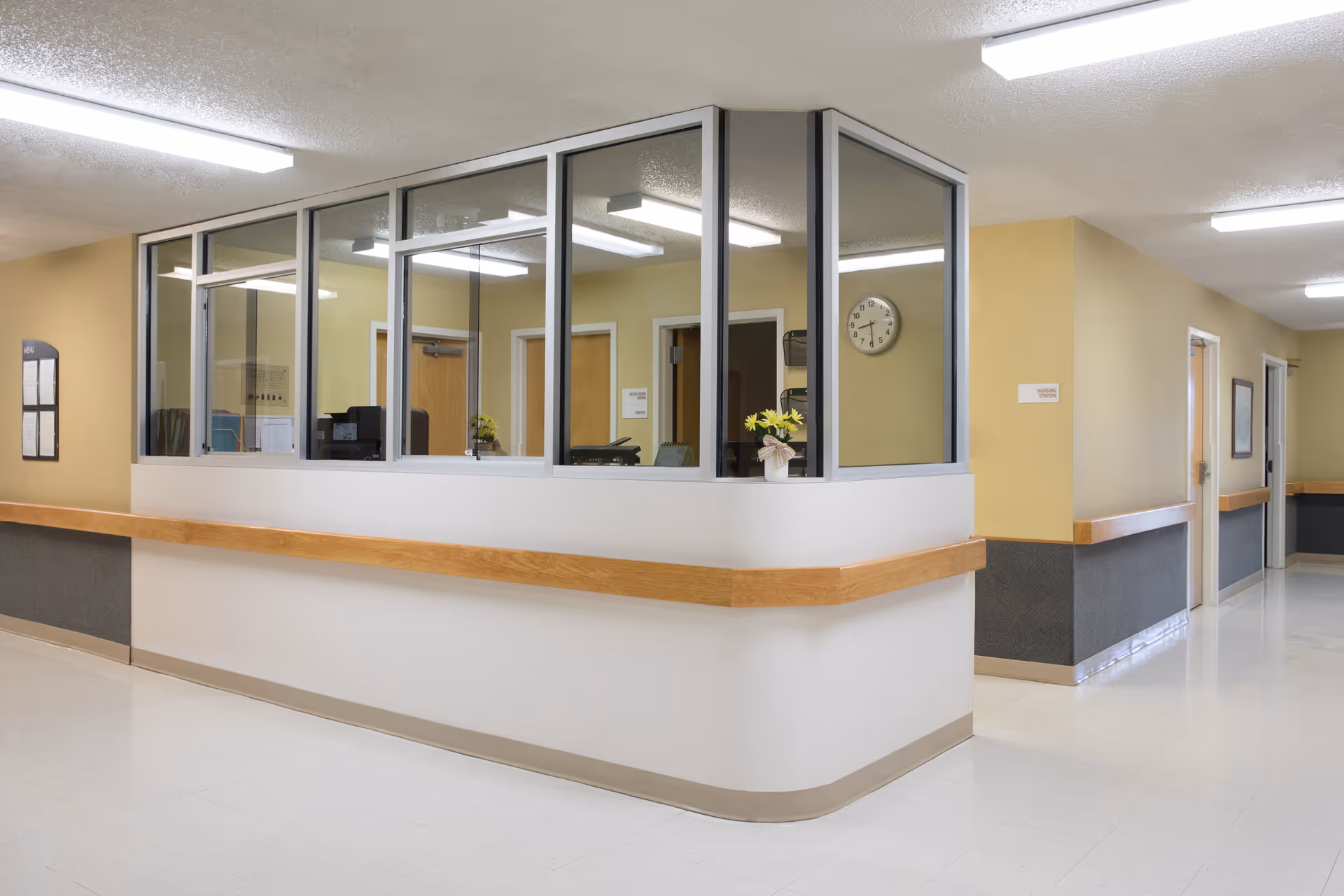 Lobby area with curved reception desk, glass partitions, and a wall clock.
