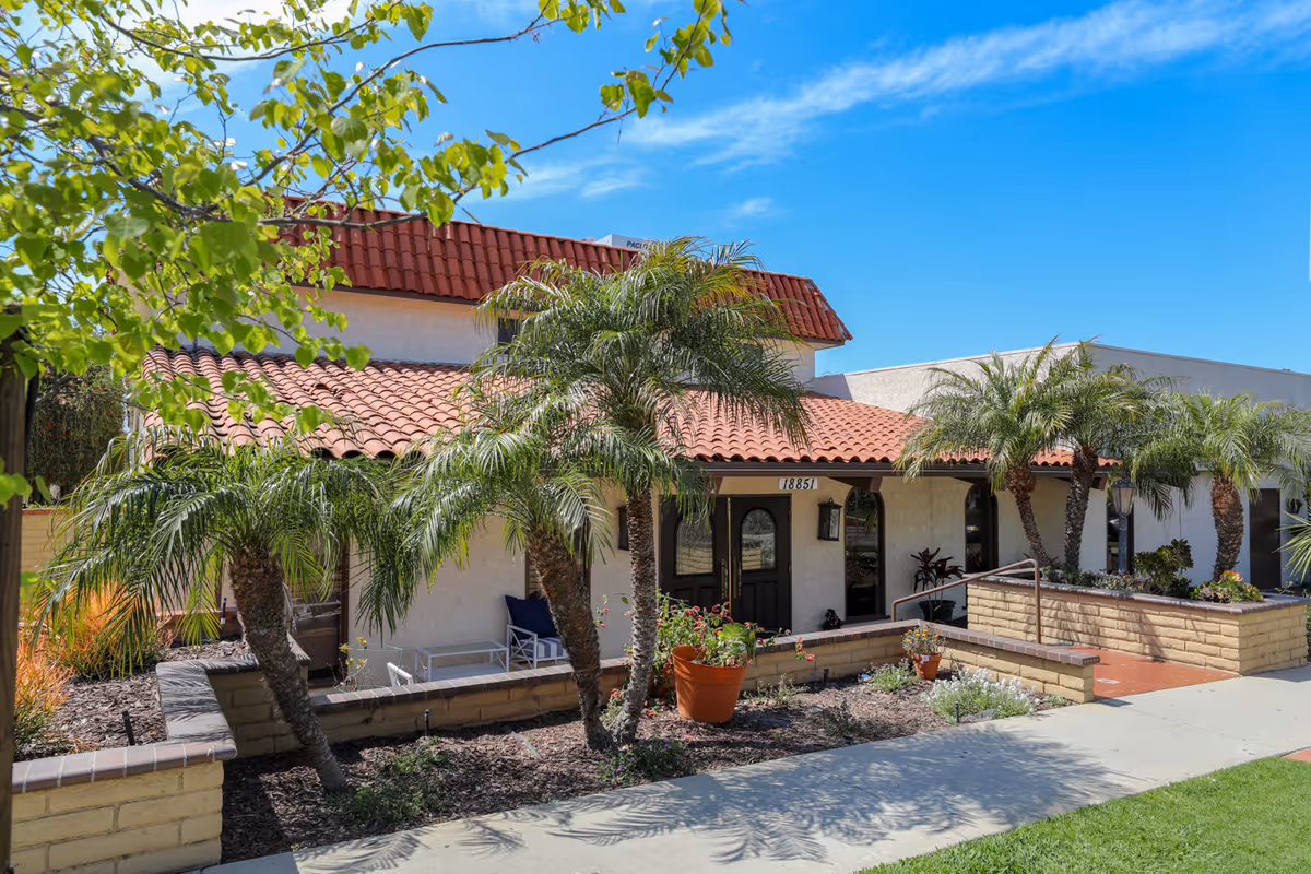 Front view of Sea Cliff Assisted Living building with red-tiled roof and palm trees