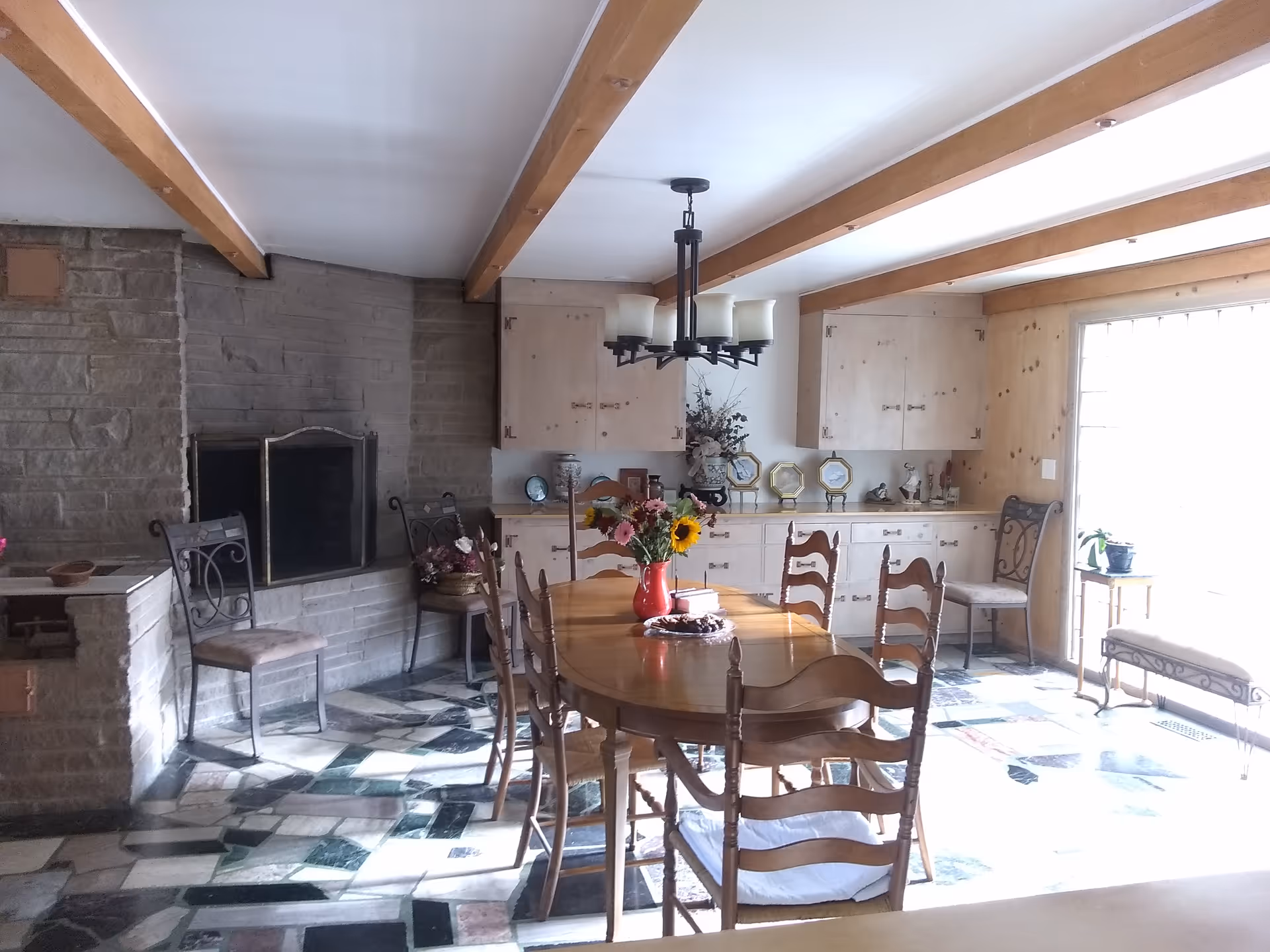 A dining room with a round table, chairs, chandelier, and built-in cabinets.