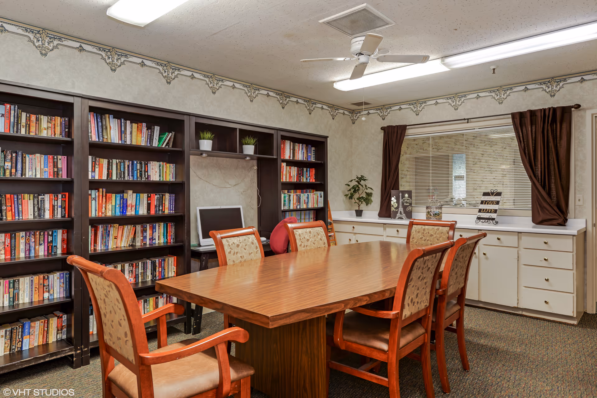 Interior library room with a long table, chairs, and tall bookshelves.