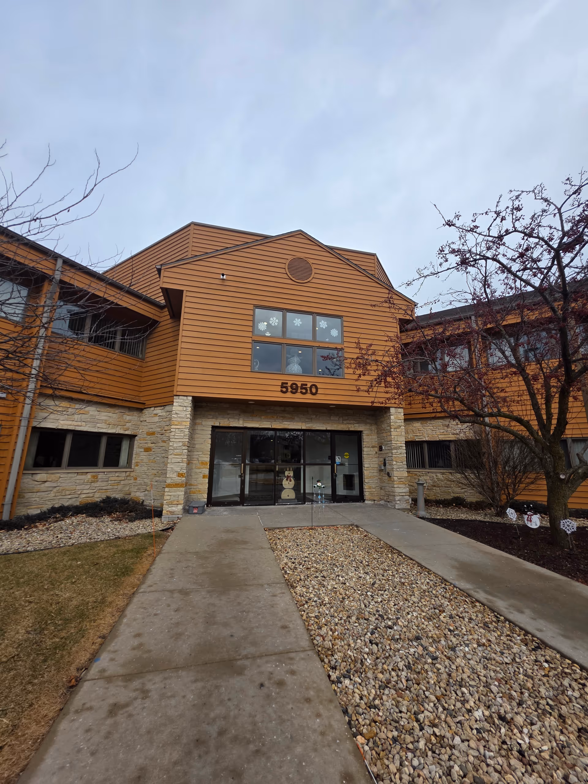 Front view of an orange-brick senior living facility entrance with glass doors.