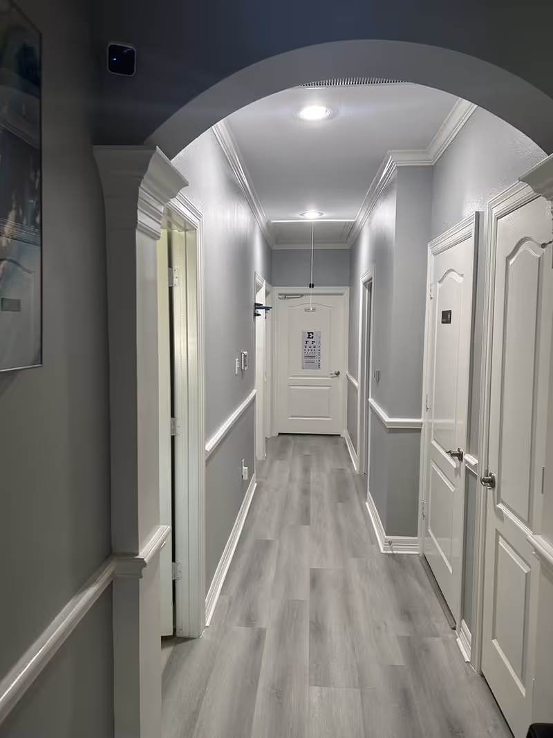 Interior hallway in a senior facility with white doors, gray flooring, and archway overhead.