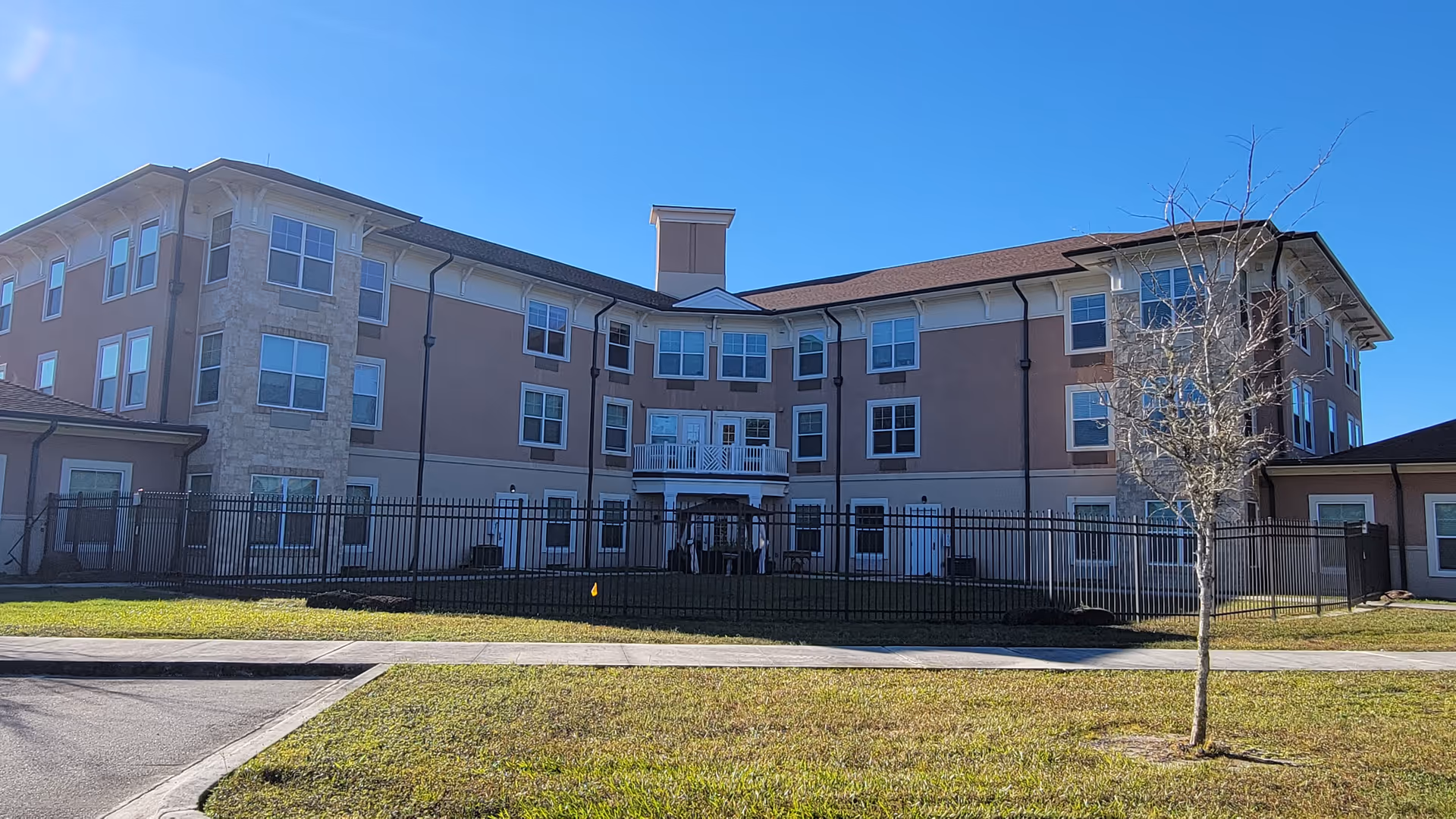 Exterior view of Canterfield of Clay County, a multi-story senior living building with a metal fence.