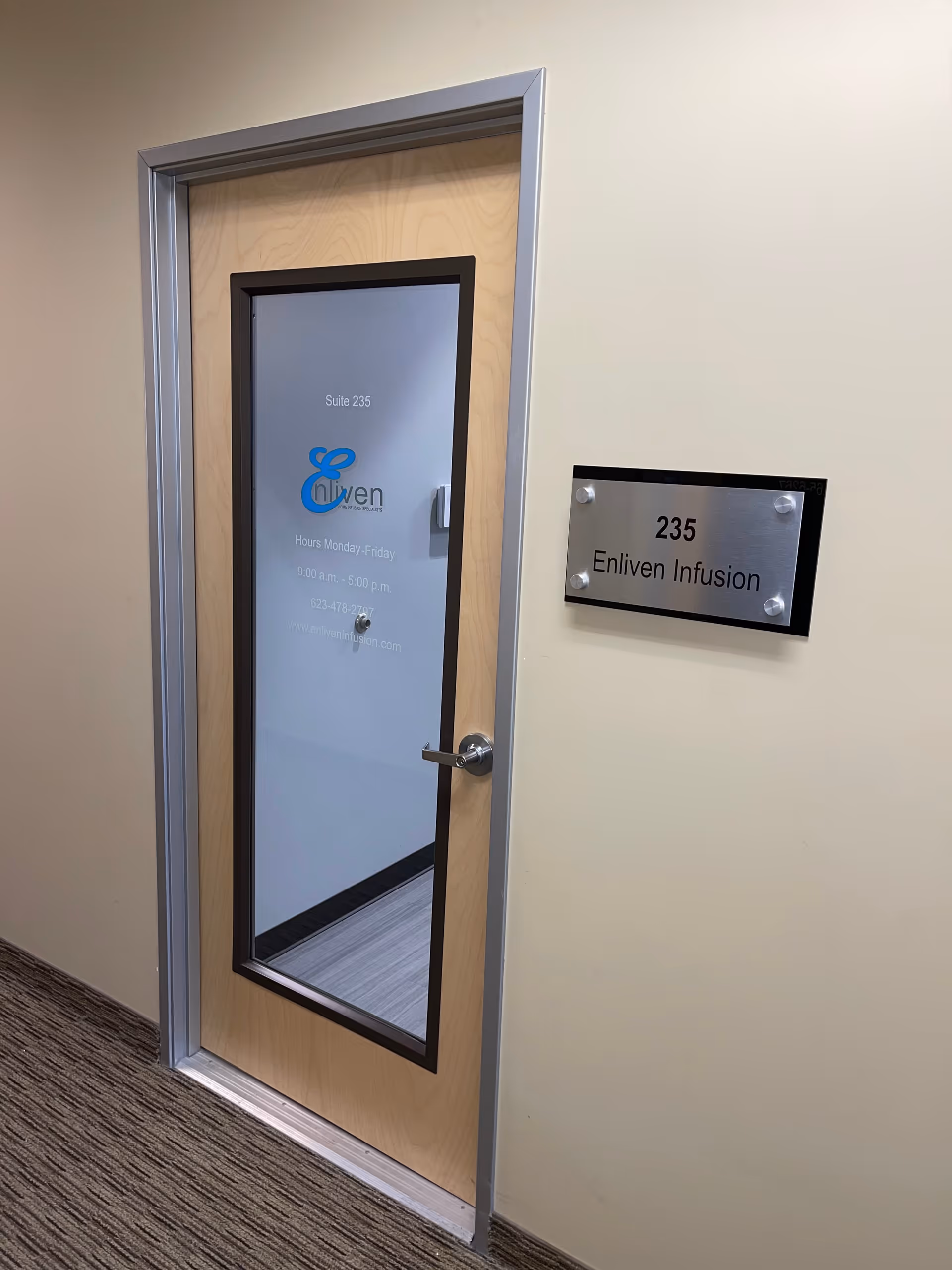 Interior hallway door with glass panel labeled Suite 235 and Enliven Infusion plaque