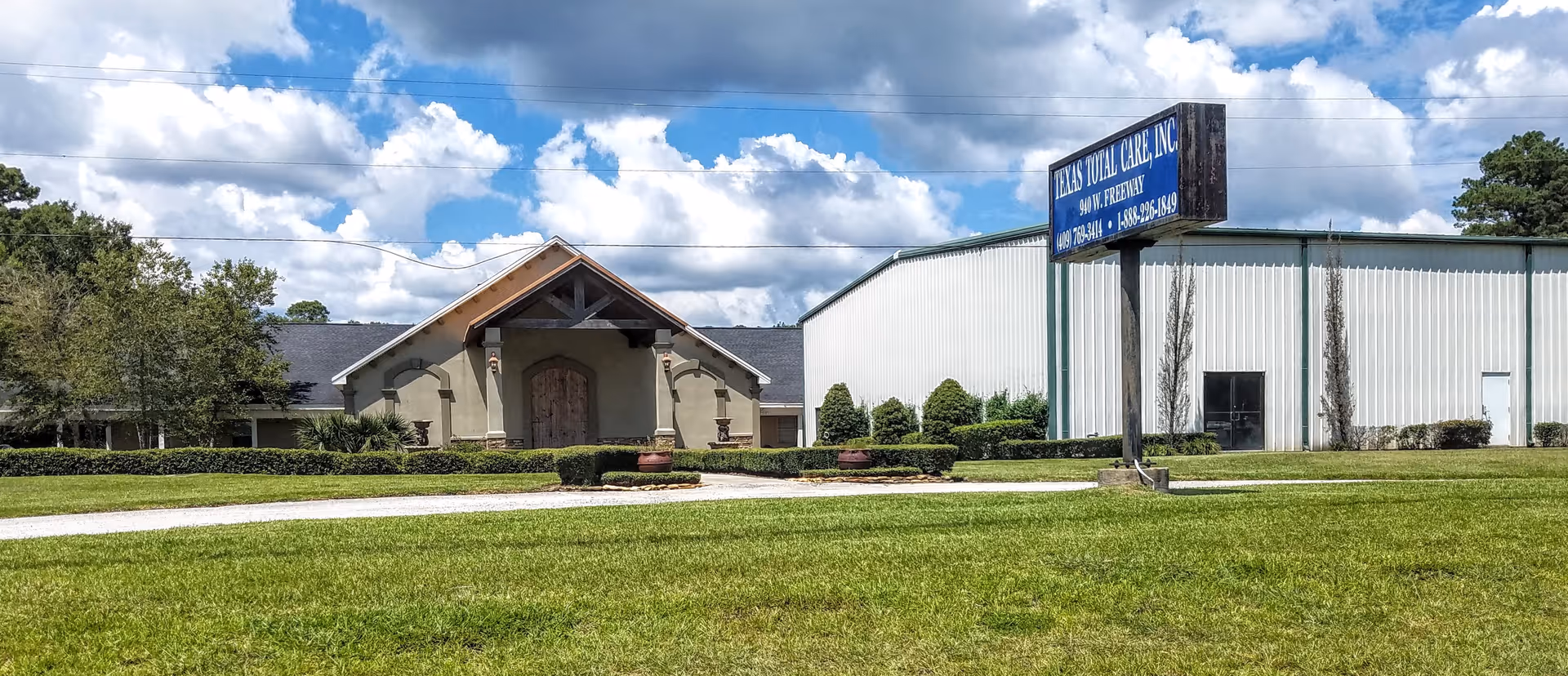 Exterior view of a Texas Total Care facility with entrance, sign, and lawn.