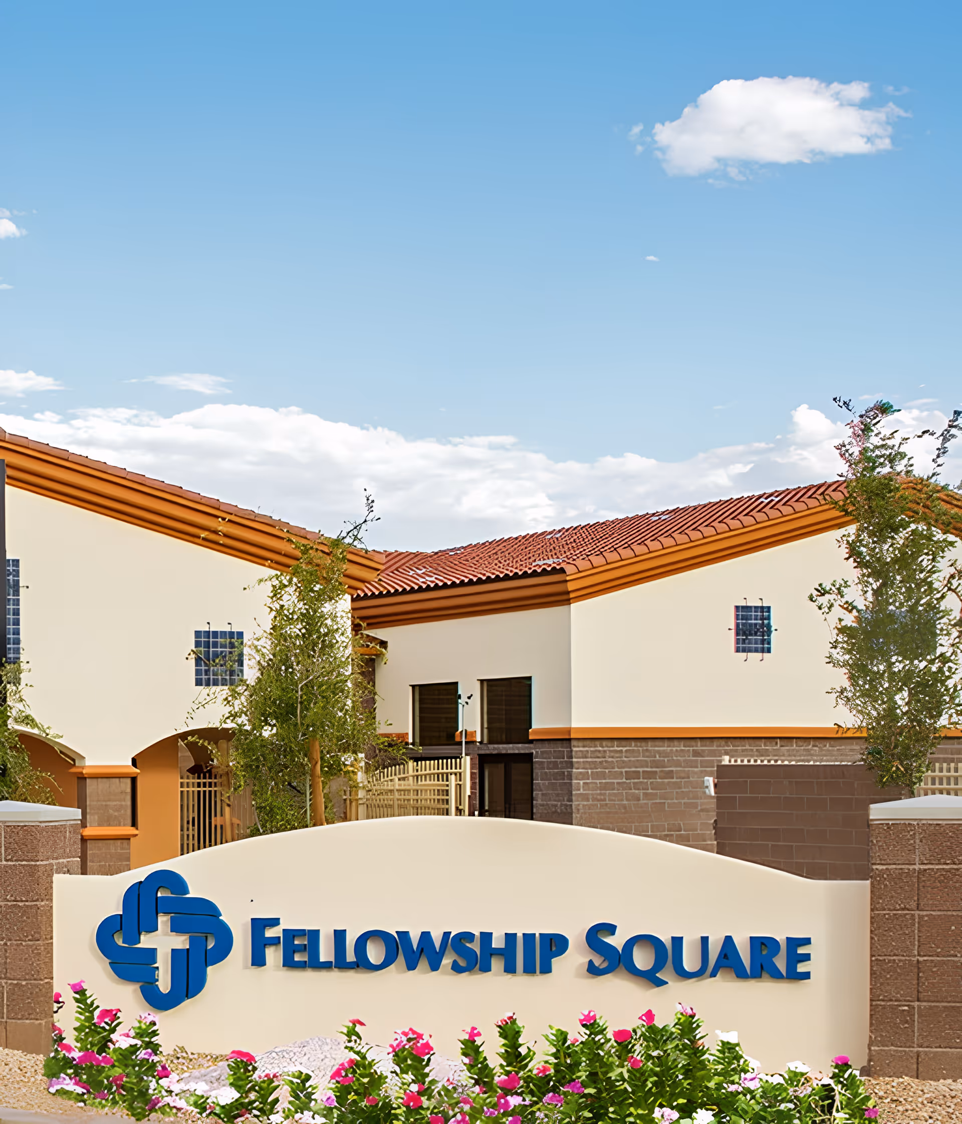 Entrance sign reading "Fellowship Square" in front of a Mediterranean-style building with red tile roofs and landscaping.