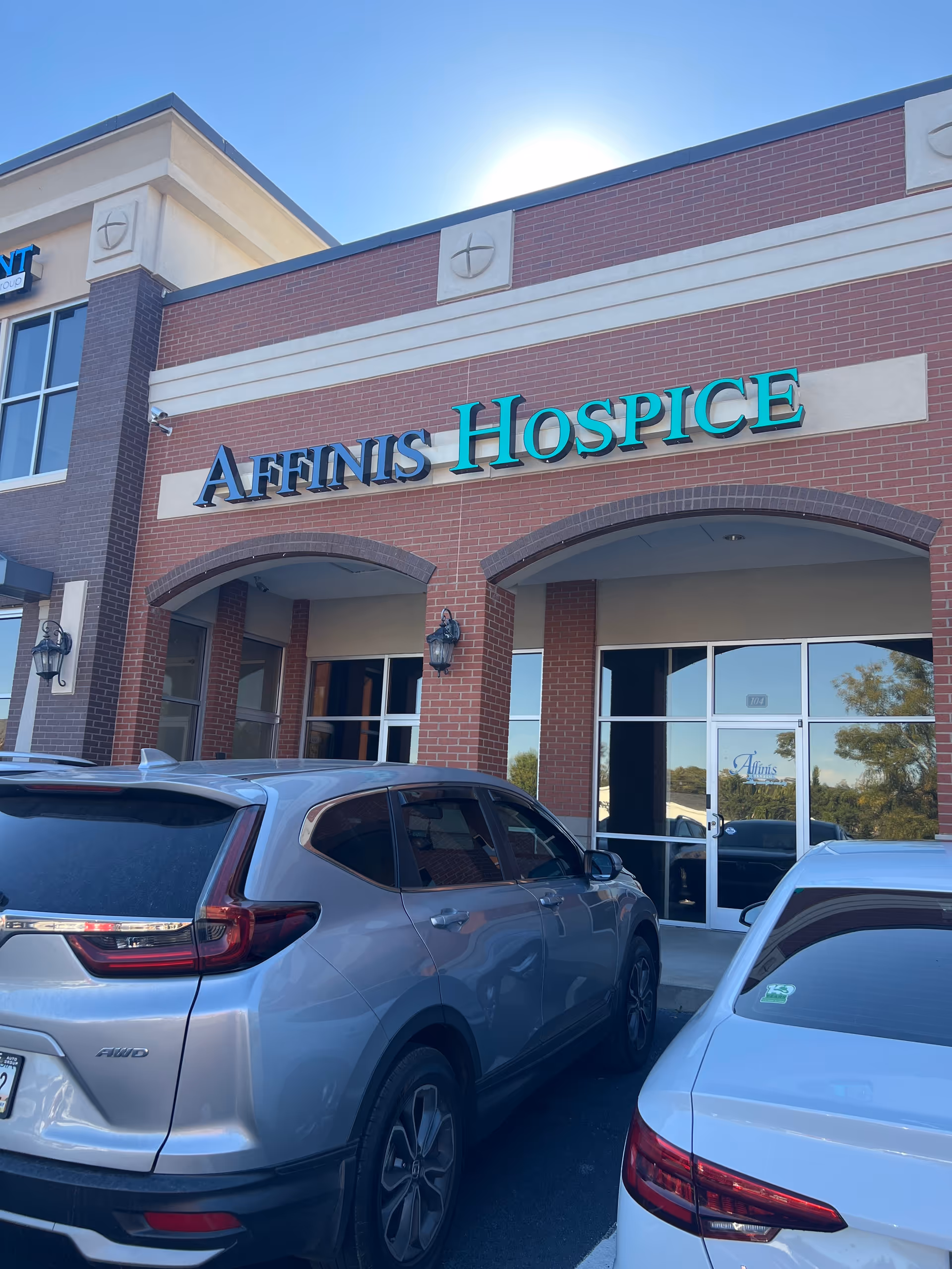 Exterior view of Affinis Hospice entrance with parked cars in front.
