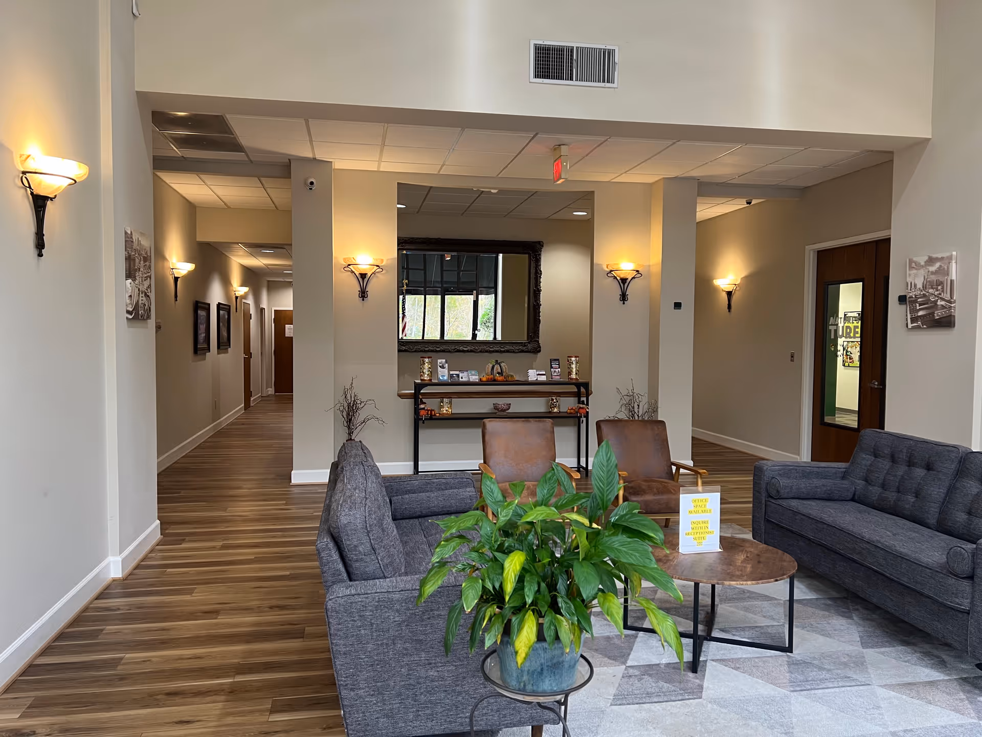 Modern senior living lobby with couches, plants, lamps, and a hallway.