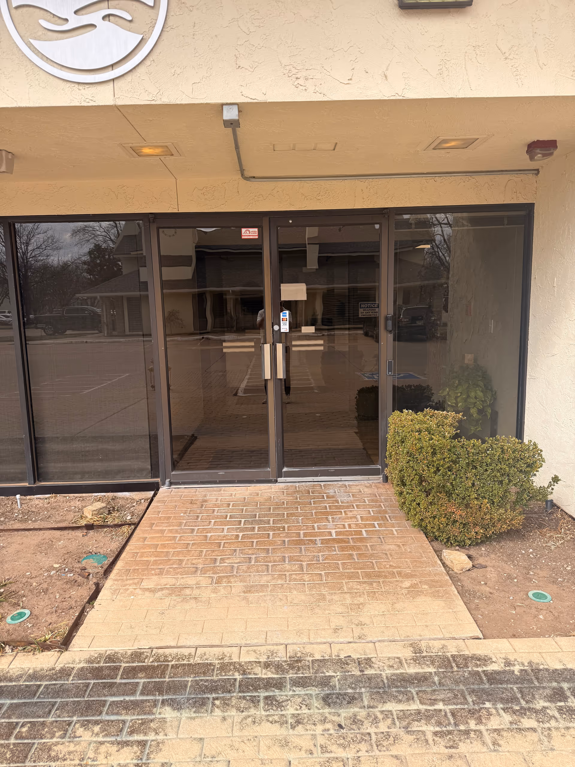 Glass front entrance of Rice Home Health facility with double doors and brick walkway