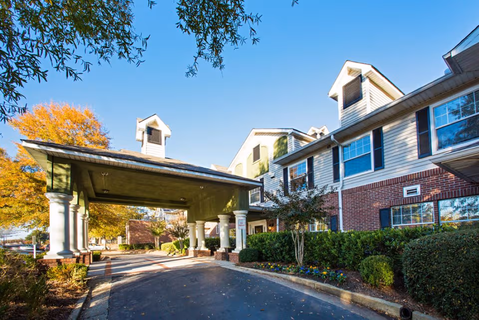 Exterior view of a senior living facility with a covered entrance and landscaped grounds.