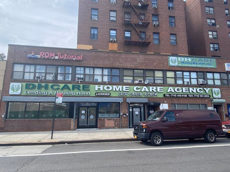 Brick storefront with DHCARE HOME CARE AGENCY signage and a maroon van parked outside.