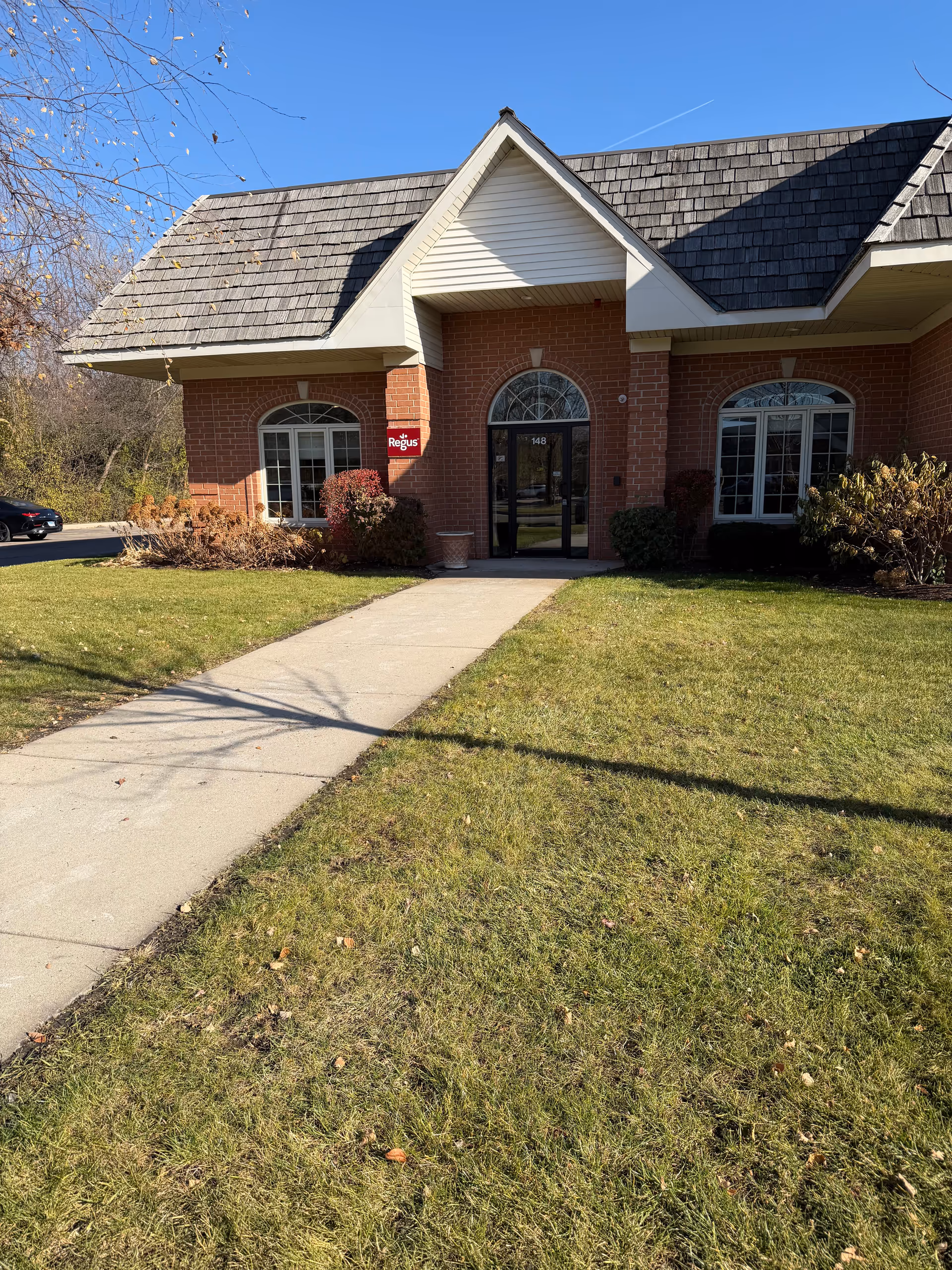 Front entrance of brick senior care facility with arched windows and a paved walkway.