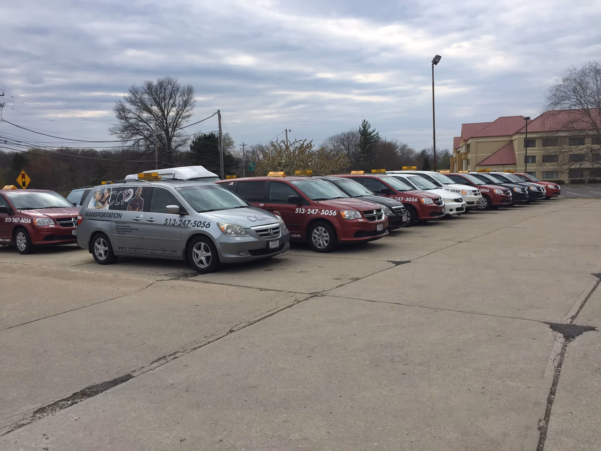 Row of transport vans parked in a lot in front of a Complete Care Providers facility.
