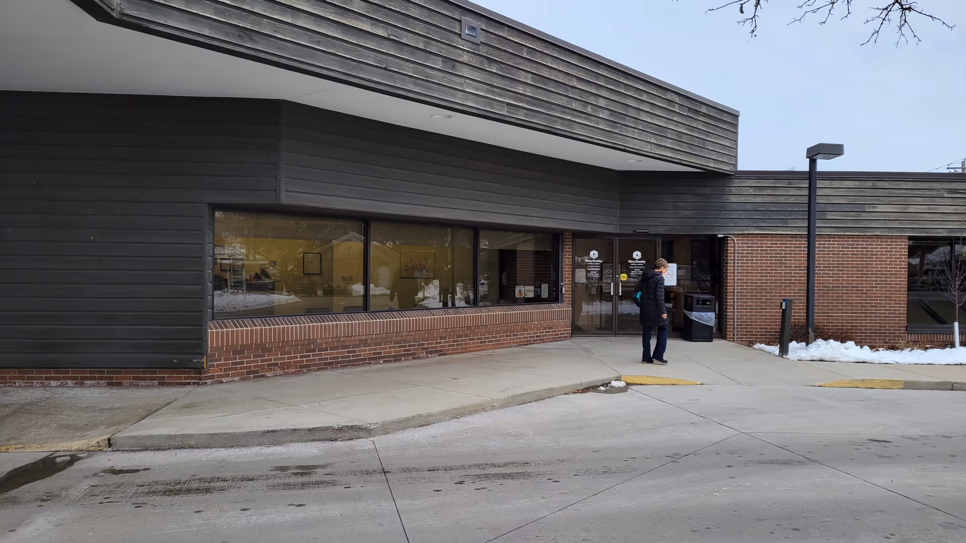 Front of Mary Greeley Home Health Services facility with glass doors and a person standing outside.