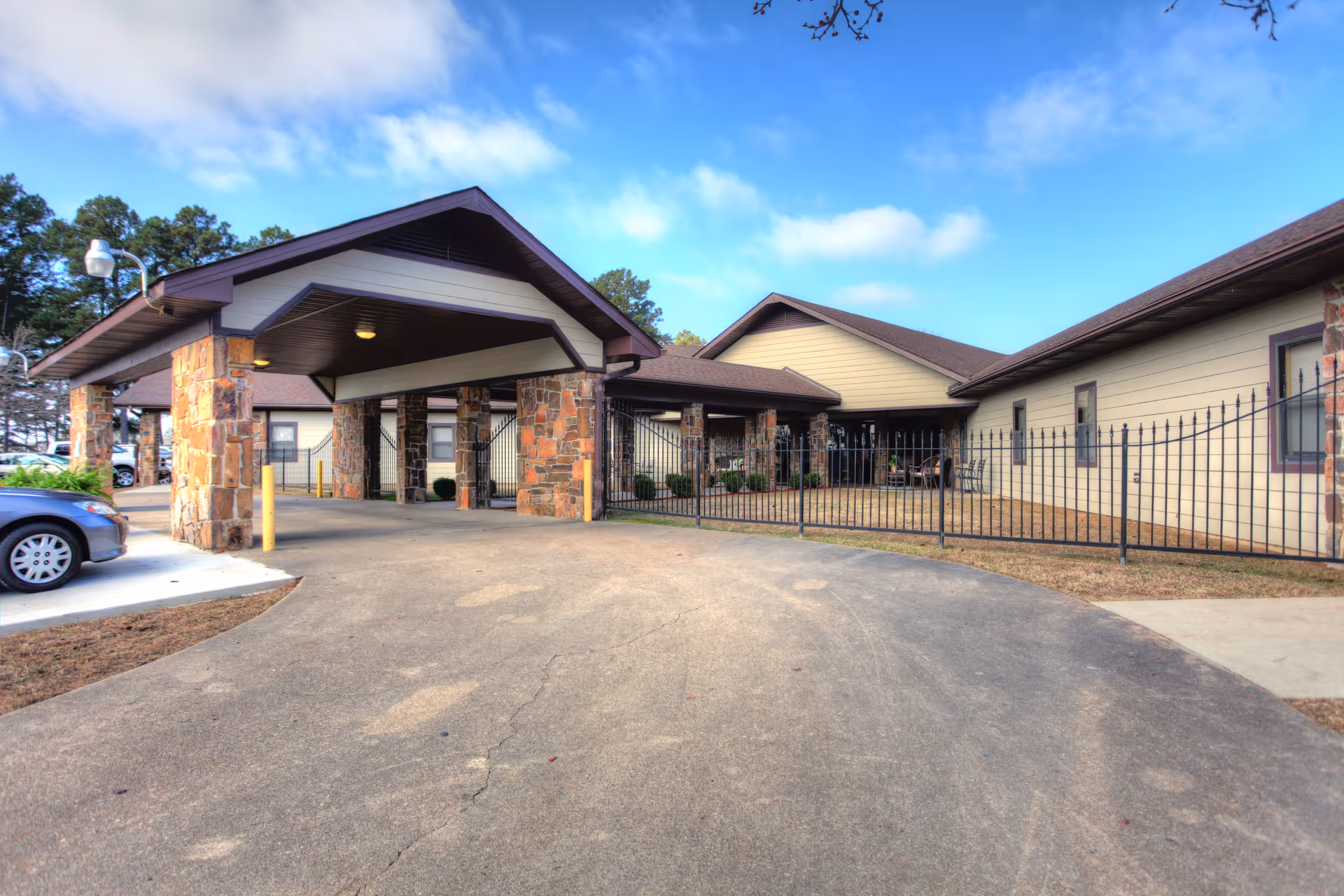 Exterior view of Pines Nursing & Rehab Center entrance with stone pillars and driveway.