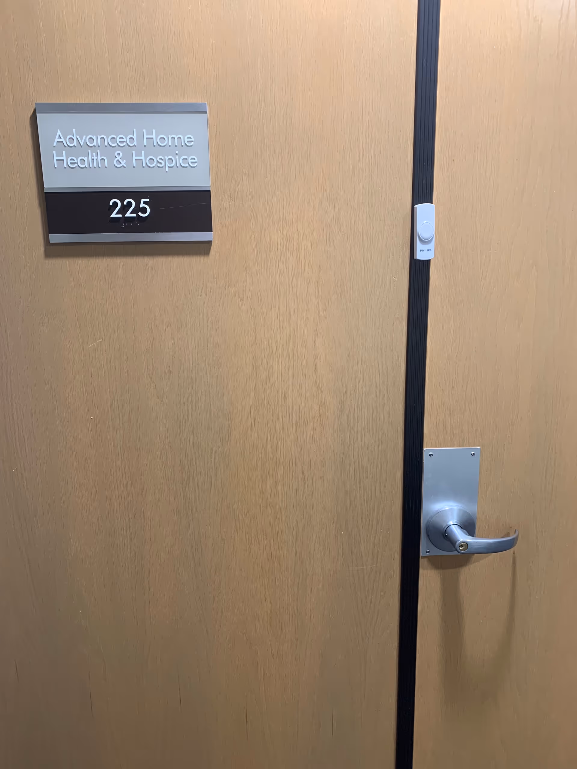 Wooden interior door with Advanced Home Health & Hospice sign and room 225.