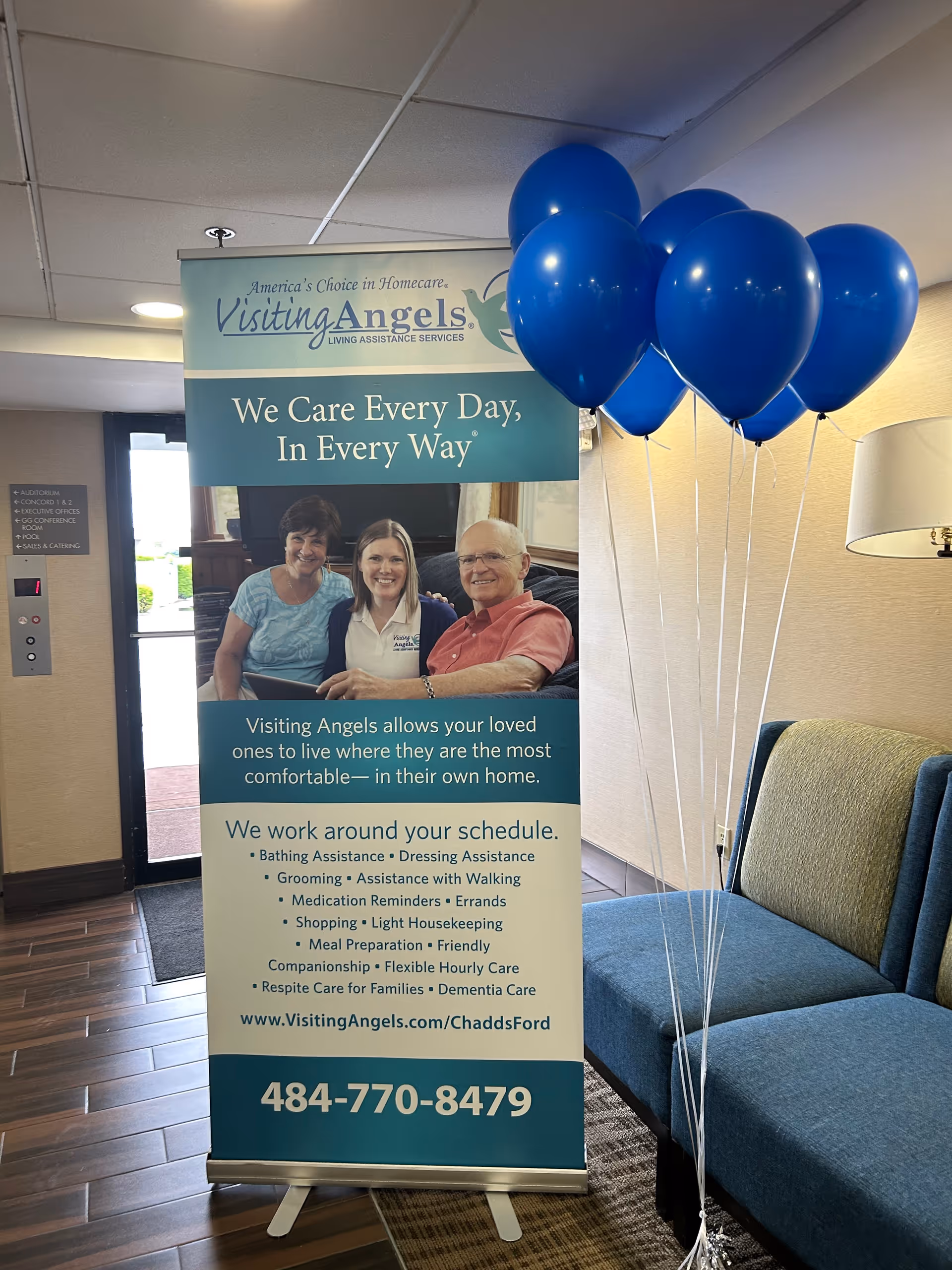 Lobby area with Visiting Angels banner, blue balloons, and blue seating.