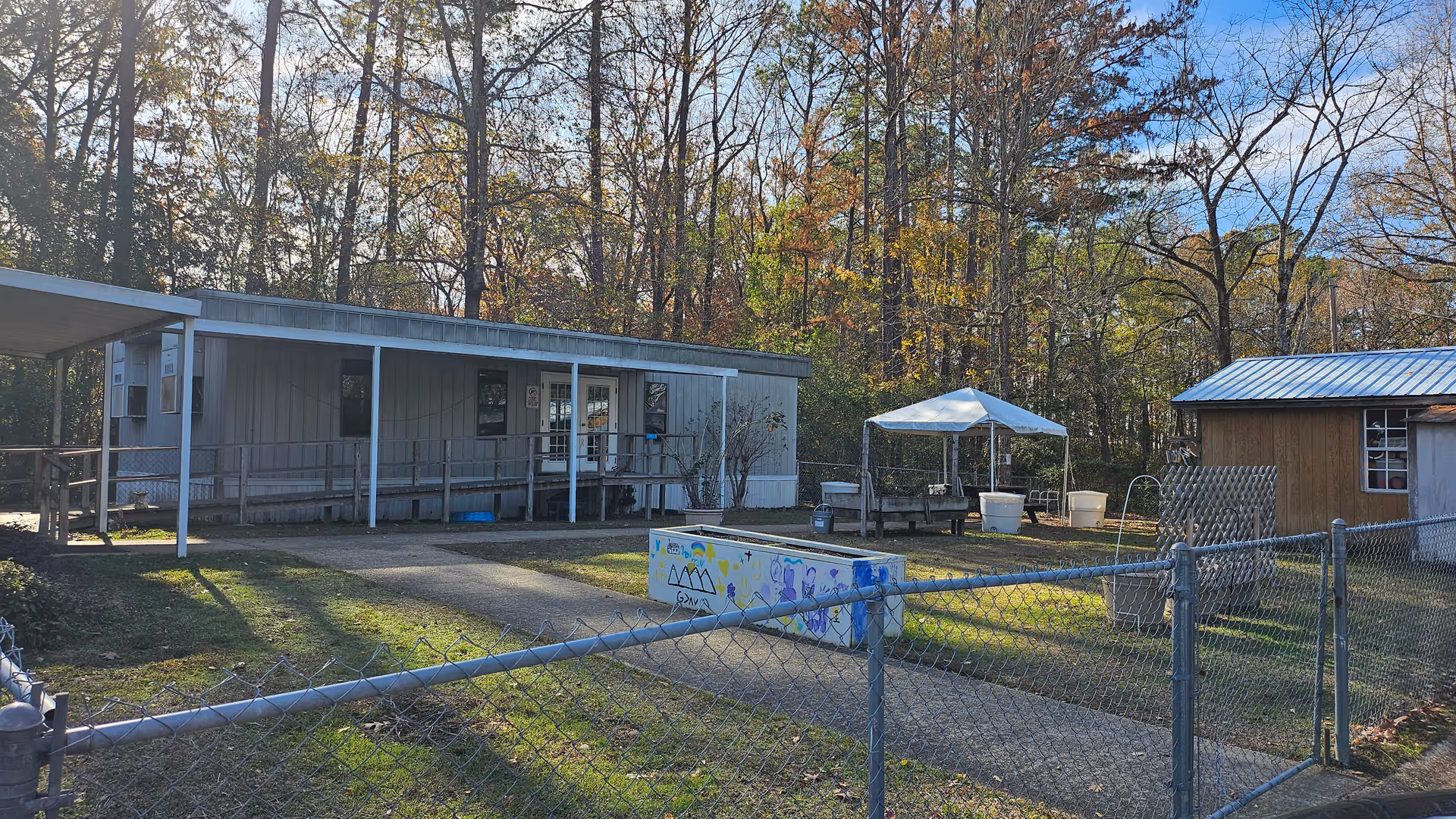 Small single-story facility with a fenced outdoor yard, pool, and shaded canopy.