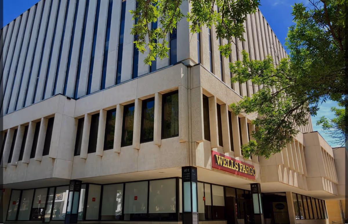 Modern multi-story commercial building with a Wells Fargo sign and large glass storefronts.