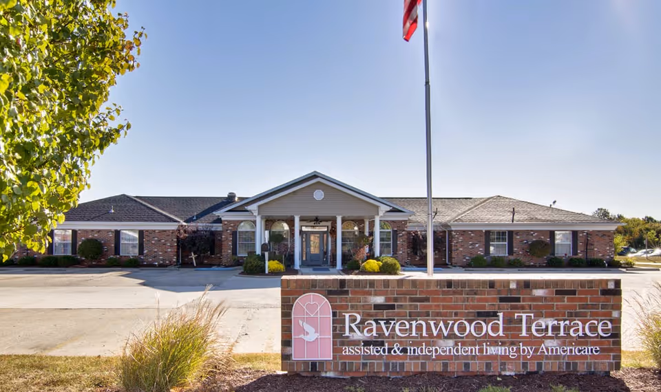 Brick senior living building with a welcoming entrance and Ravenwood Terrace sign.