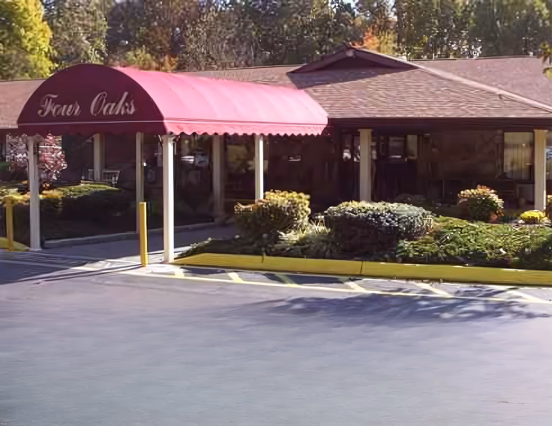 Exterior view of Four Oaks Healthcare Center entrance with pink awning and landscaping