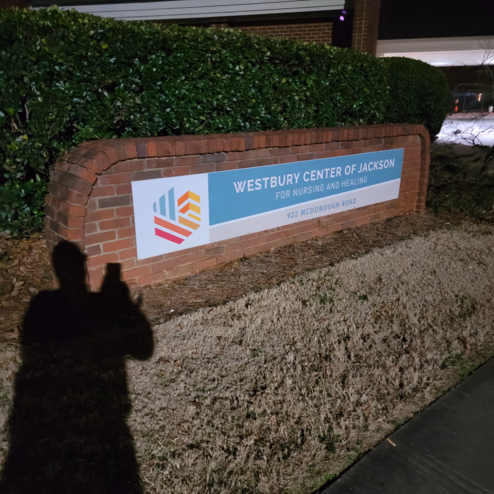 Exterior brick sign for Westbury Center of Jackson for Nursing and Healing with hedges.