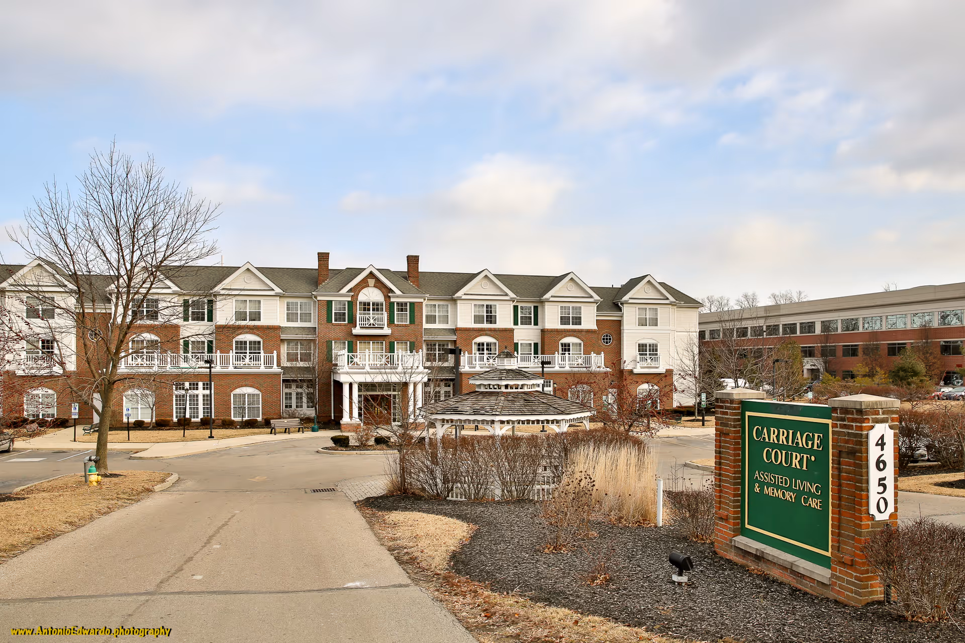 Exterior view of Carriage Court of Kenwood senior living building with front entrance and sign.