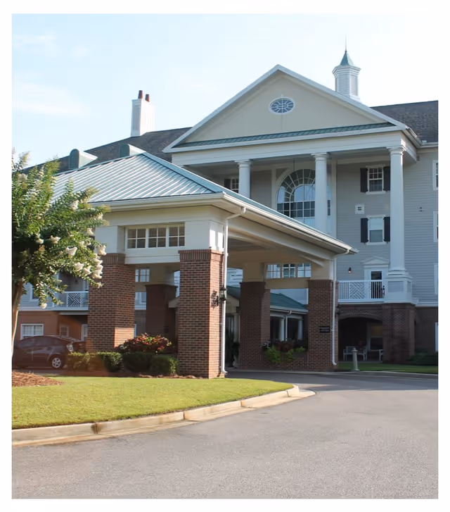 Exterior view of a large senior care facility with brick pillars and a covered entry.