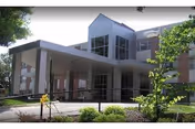 Modern senior living facility exterior with glass entrance and covered drop-off area.