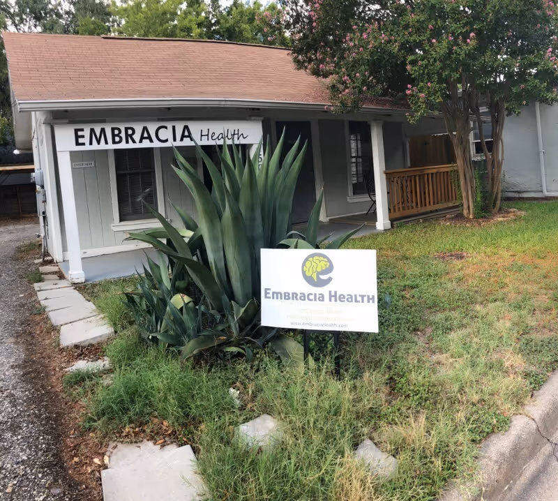 Exterior view of Embracia Health facility with front entrance and surrounding landscaping.