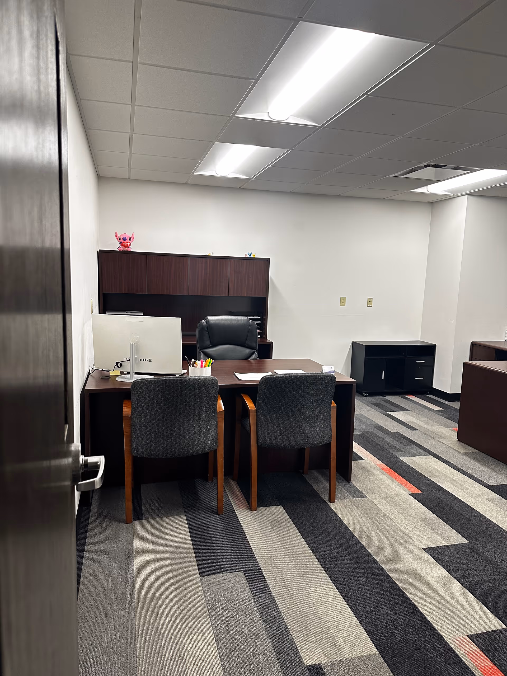 Office desk with chair, computer, and filing cabinet in a clean, well-lit facility workspace.