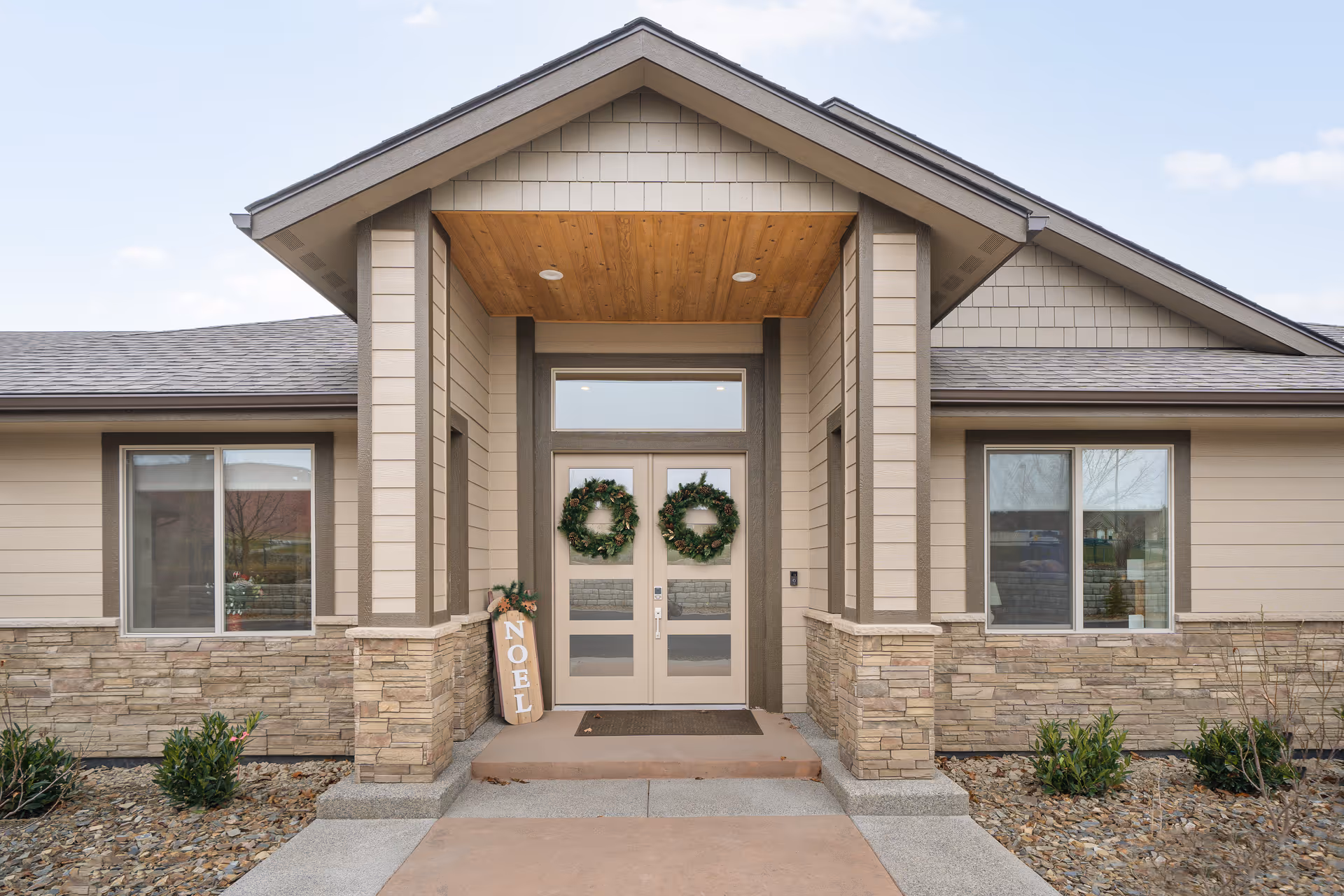 Front entrance of a modern senior living facility with double doors and decorative wreaths.