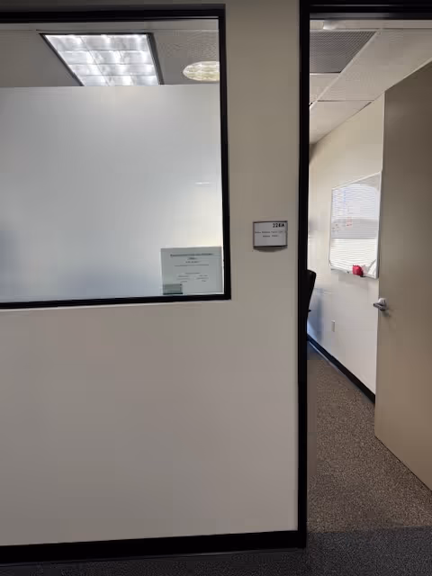 Interior hallway with frosted glass window and an open door to a small room.