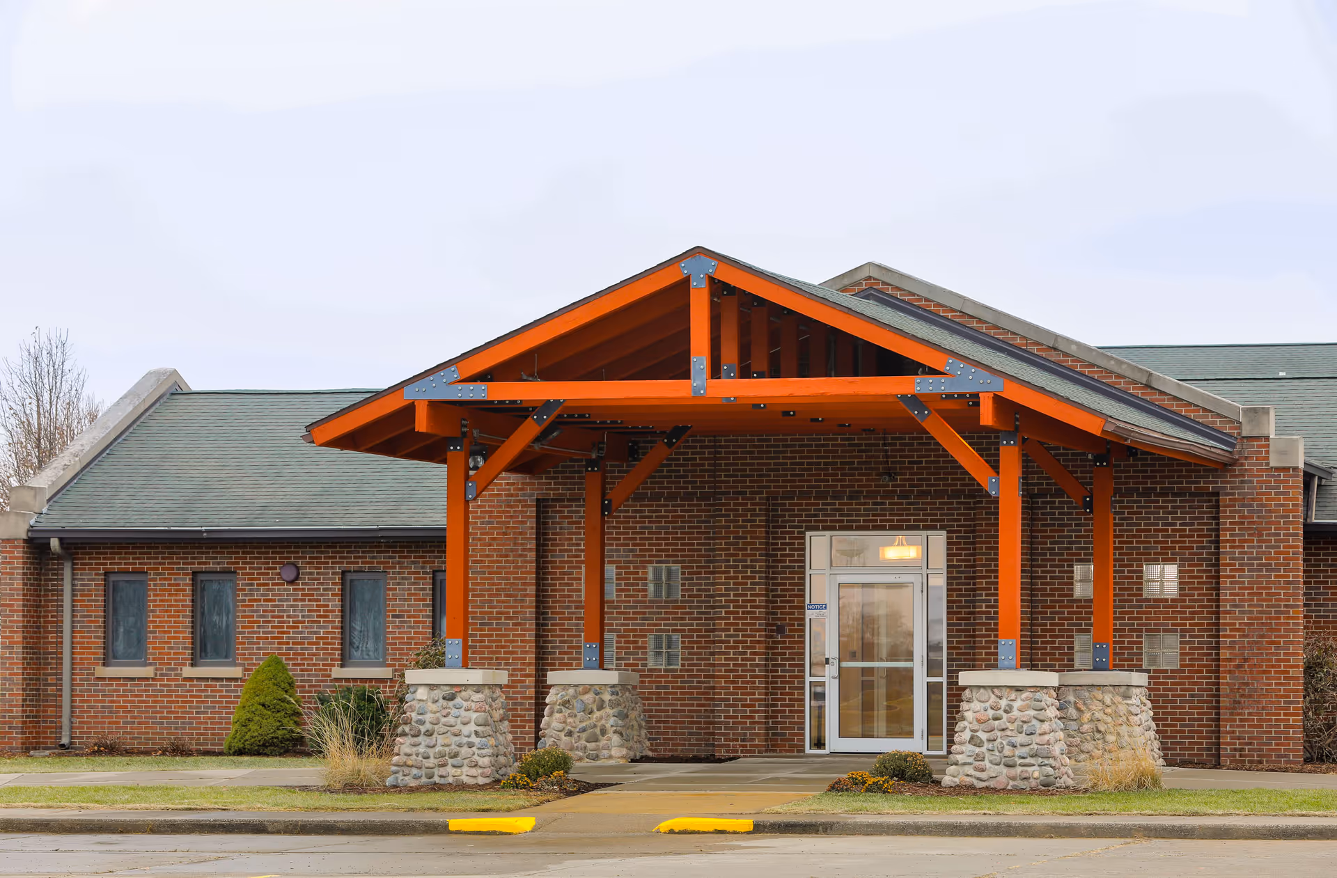 Exterior view of a brick senior living facility entrance with orange portico