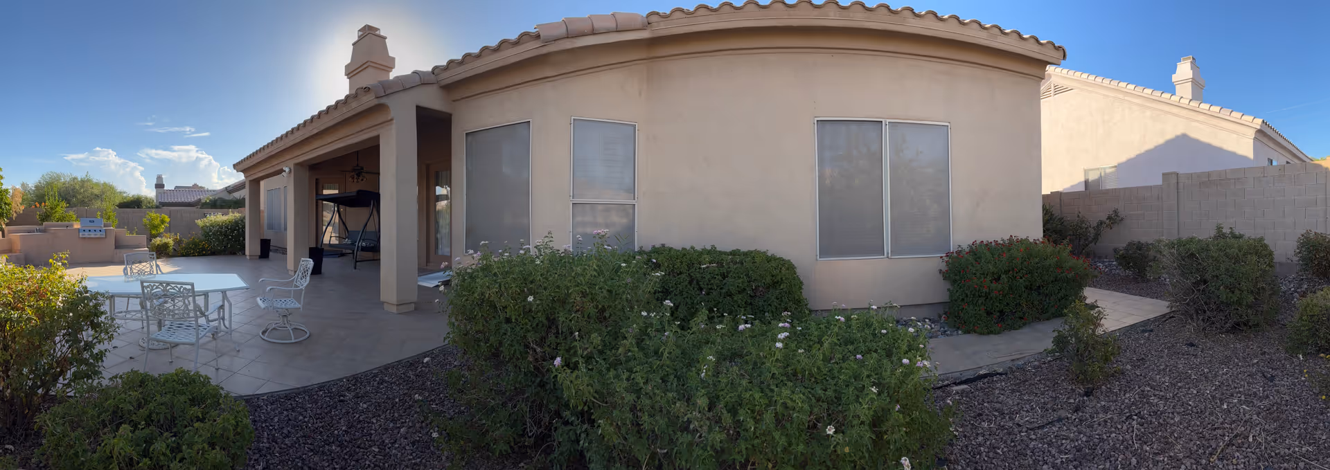 Single-story beige assisted living building with covered patio and outdoor seating.