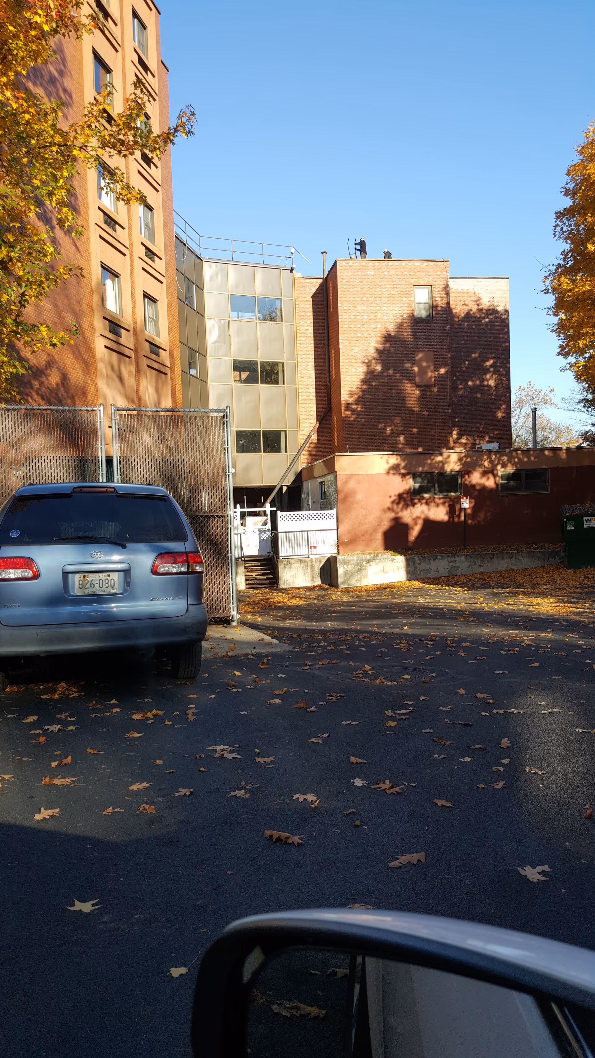 Exterior view of Summit Commons with brick buildings, a parked car, and autumn leaves.