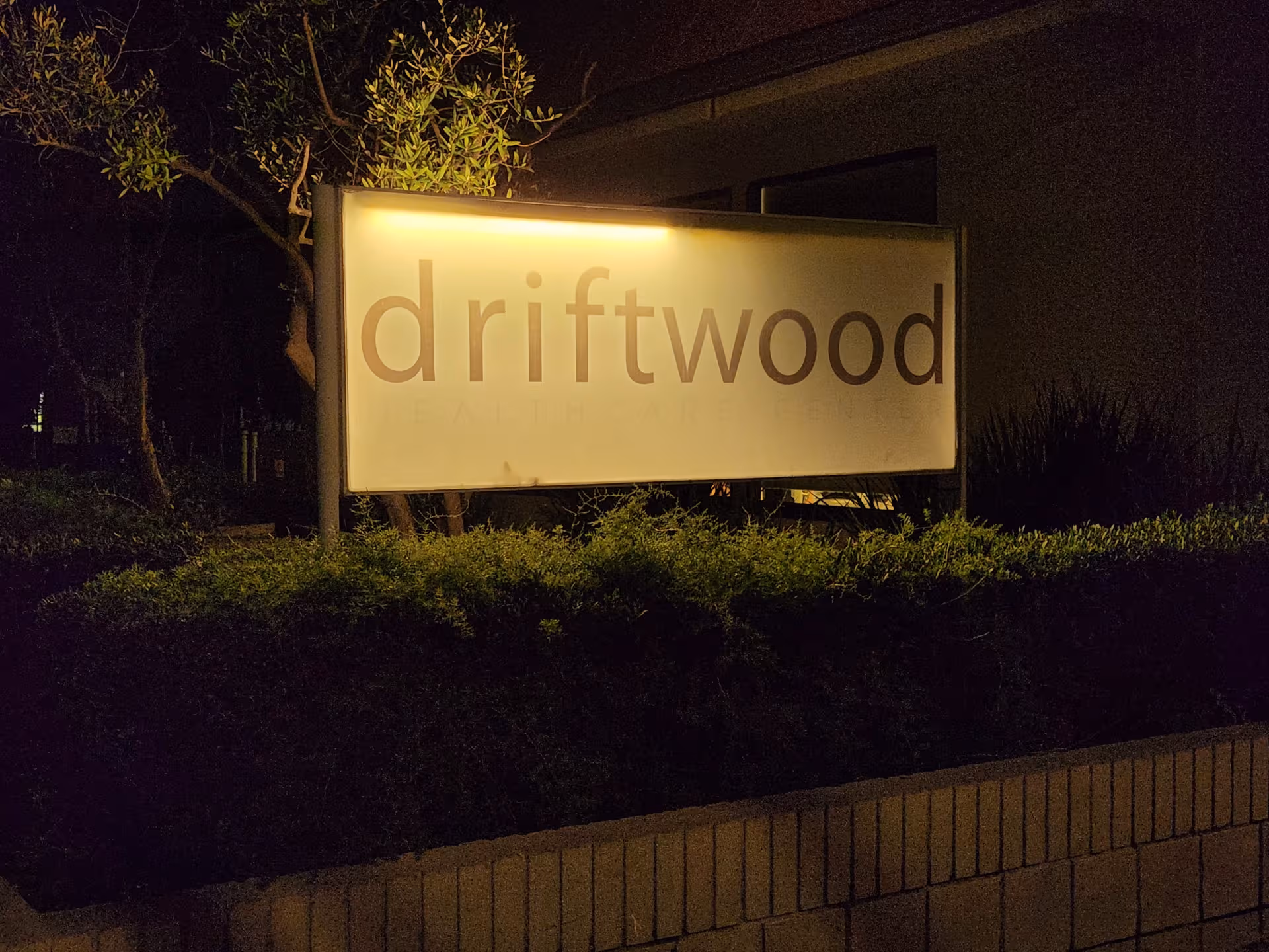 Nighttime exterior of Driftwood Healthcare and Rehabilitation Center sign lit at the front.
