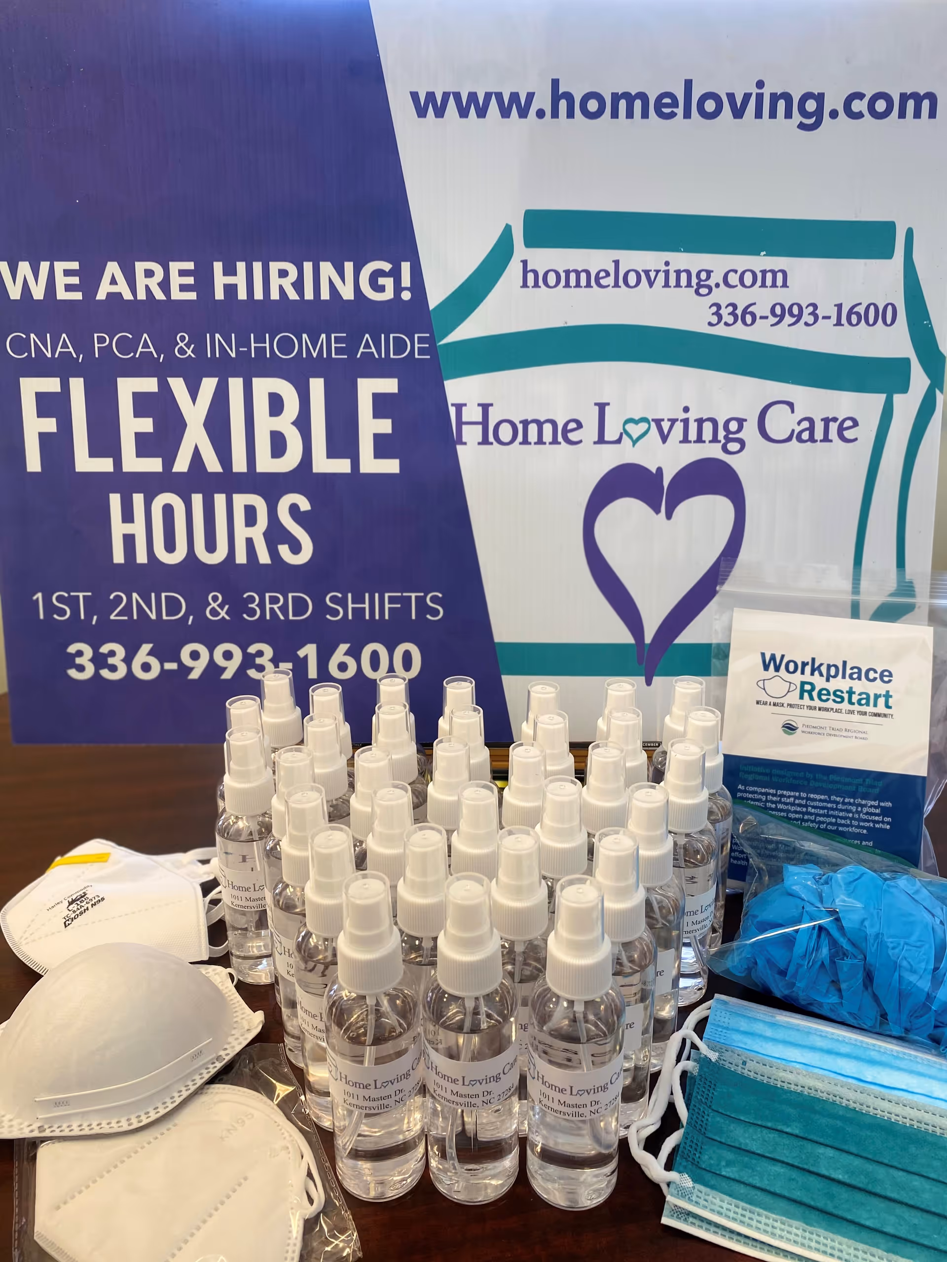 Table with hand sanitizer bottles, masks, and PPE against a Home Loving Care banner.
