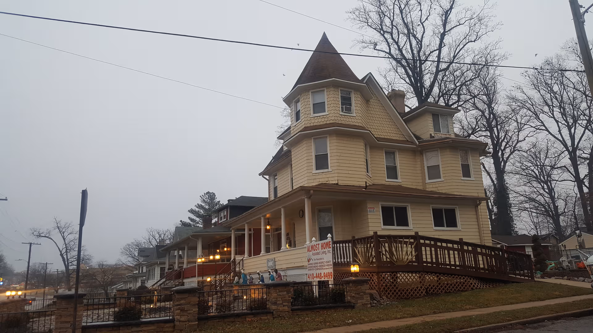 Beige, multi-story assisted living building with turret, front porch, and visible sign.