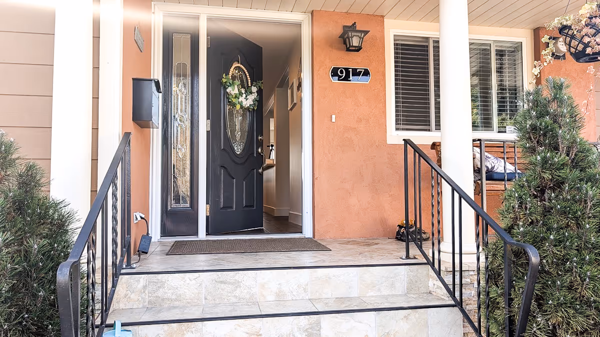 Open front door of an orange stucco building with wreath and porch steps.