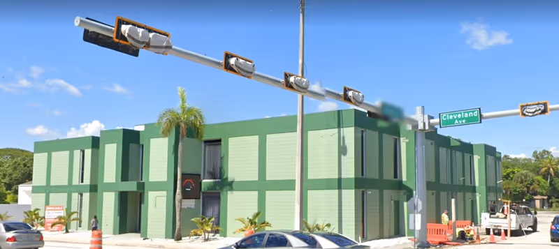 Exterior view of a green facility building at a busy street intersection.