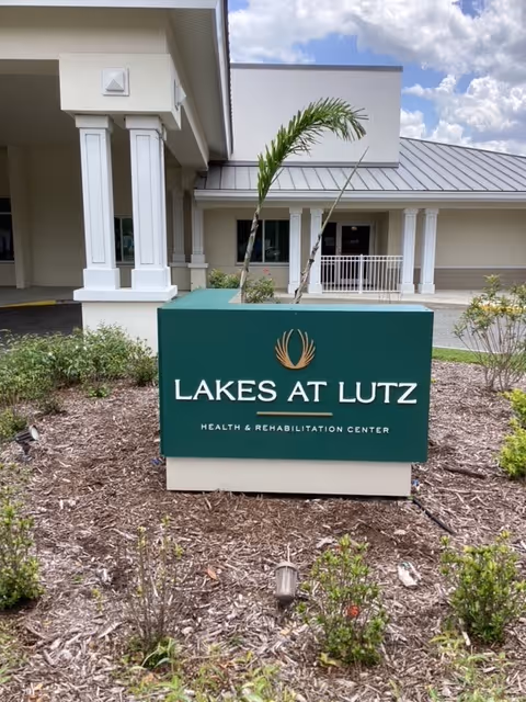 Exterior view of Lakes at Lutz sign with entrance and landscaped front of the health center.