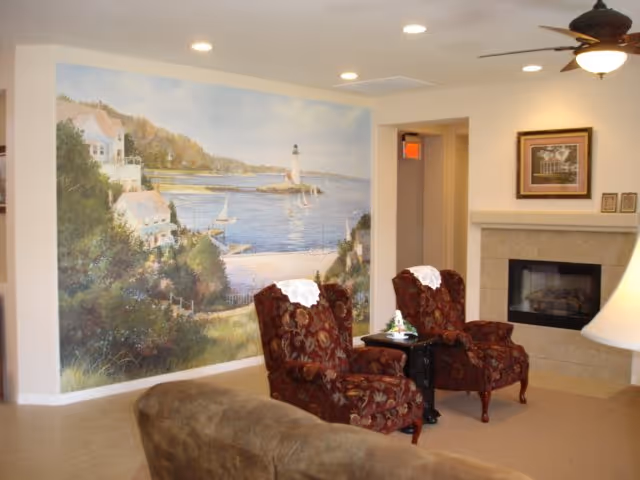 Interior living room lounge with red chairs, table, fireplace, and seaside mural.