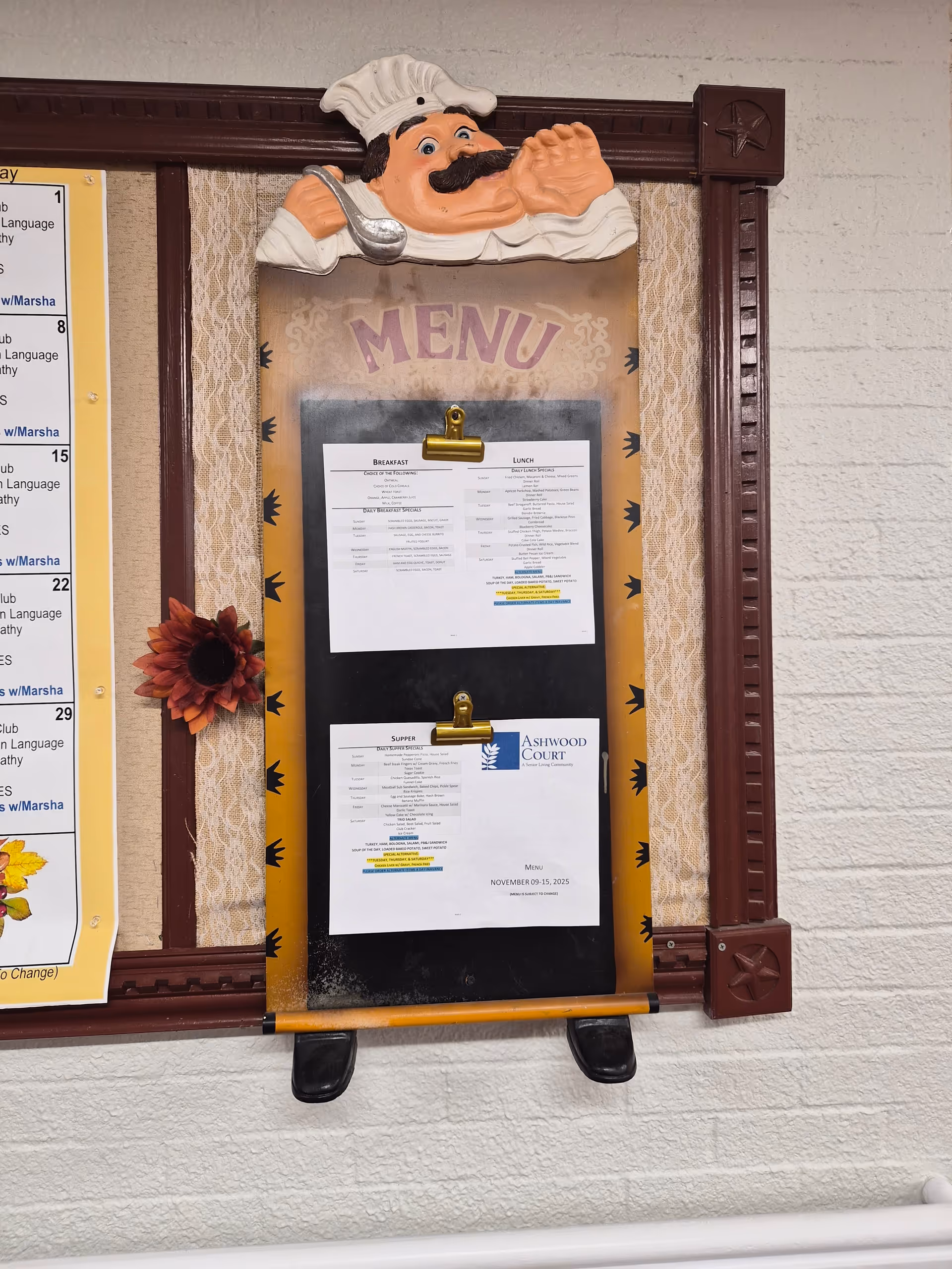 Exterior wall menu board with a chef sculpture and Ashwood Court signage.